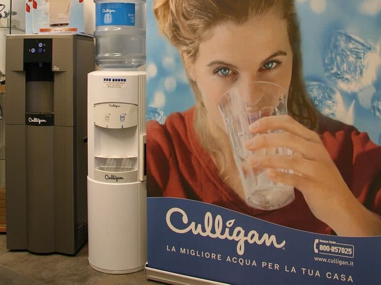 Gli erogatori d'acqua Culligan accanto al manifesto «La migliore acqua per la tua casa»